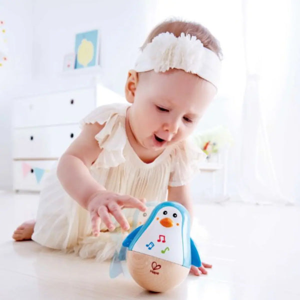 Baby playing with Hape Penguin Musical Wobbler – safe, non-toxic wooden toy that makes soft tinkling sounds, available in Kenya from Cheza Plus.