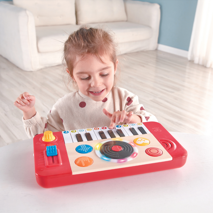 Girl playing with Hape DJ Mix & Spin Musical Toy – fun interactive DJ set that helps develop rhythm and coordination, sold by Cheza Plus Kenya.
