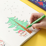 Hand coloring a Christmas tree illustration in a colouring book with a green marker.